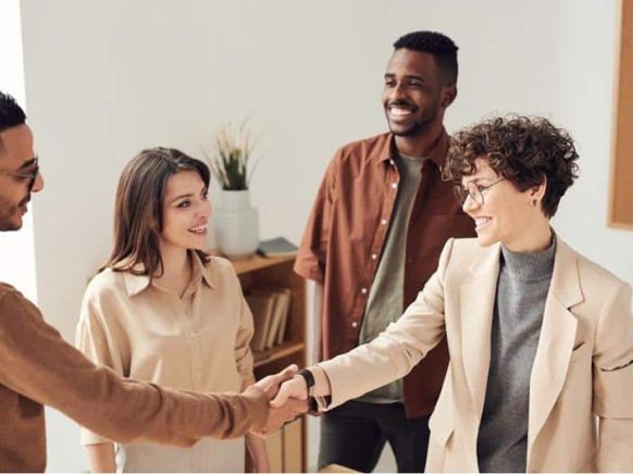 People shaking hands in a professional business meeting, representing successful client-agency relationships and lead generation.
